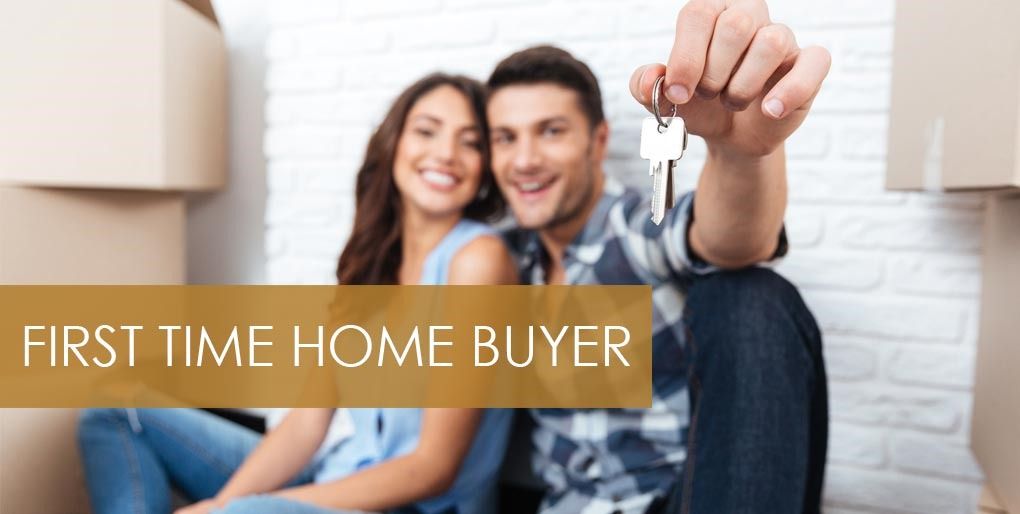 A smiling couple sitting among moving boxes, one holding up a house key, under the words First Time Home Buyer